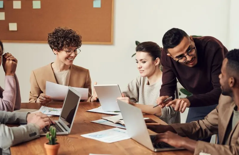 Equipe em volta de uma mesa com notebooks, conversando